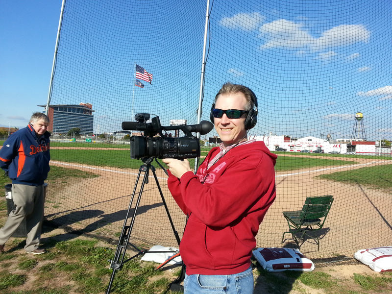 Director Jason Roche poses with his camera behind home plate in Oct. 2013.